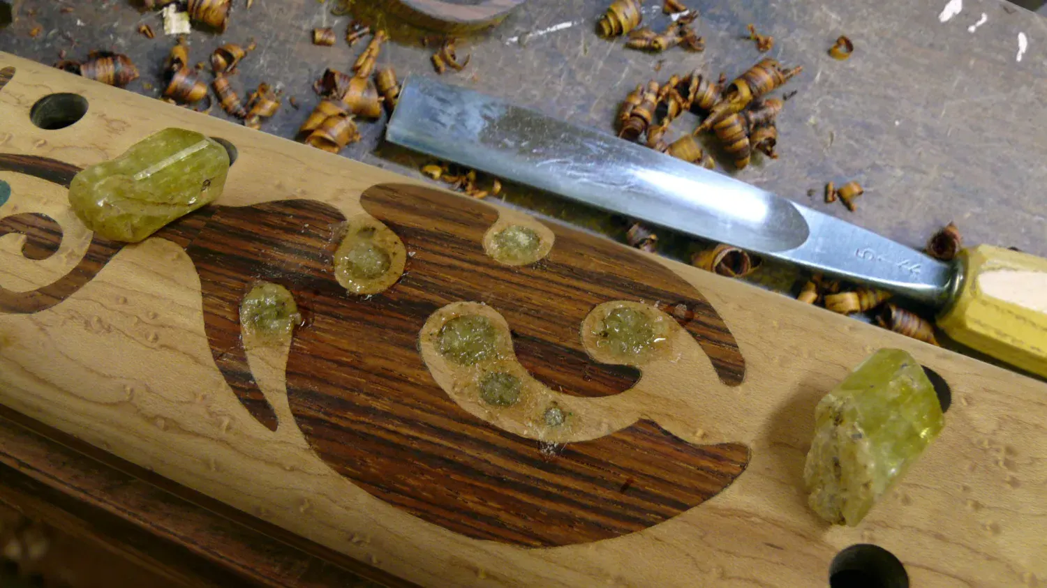 Crushed stone inlay set into a flute body, with raw stone nearby
